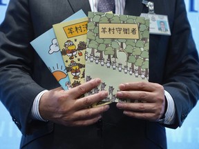 Li Kwai-wah, senior superintendent of Police National Security Department, poses with evidence including three children's books on stories that revolve around a village of sheep which has to deal with wolves from a different village, before a press conference in Hong Kong Thursday, July 22, 2021.
