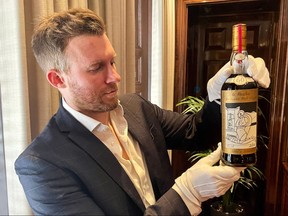 A member of staff shows a bottle of the Macallan Valerio Adami 60 Year Old 42.8 abv 1926 during a photocall at the auction house Sotheby's in London, on Oct. 19, 2023.