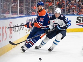 Winnipeg Jets' Rasmus Kupari (15) and Edmonton Oilers' Darnell Nurse (25) battle for the puck during first period NHL action in Edmonton, Saturday, Oct. 21, 2023.