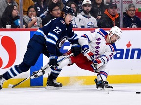 New York Rangers' Chris Kreider (20) passes the puck as he is checked by Winnipeg Jets' Mason Appleton (22) during second period NHL action in Winnipeg on Monday October 30, 2023.