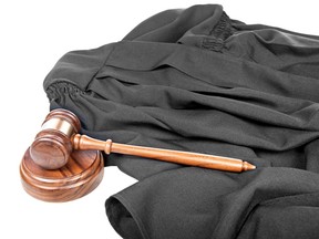 A judge’s black gown and wooden gavel with sound block.
