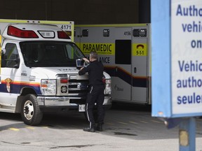A paramedic works on a laptop on the hood of their ambulance, outside the Emergency Department at the Ottawa Hospital Civic Campus in Ottawa on Monday, May 16, 2022.
