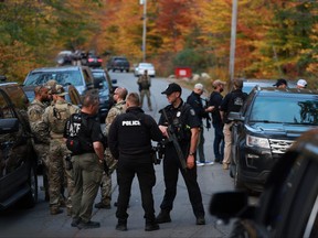 Law enforcement officials gather in the road leading to the home of the suspect being sought in connection with two mass shootings on Oct. 26, 2023 in Bowdoin, Maine.