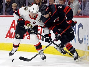 The Ottawa Senators' Brady Tkachuk battles for the puck against the Carolina Hurricanes' Brett Pesce during the first period in Raleigh, N.C., Wednesday, Oct. 11, 2023.