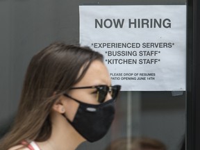 A pedestrian wearing a mask walks past help wanted signage at Queen’s Pasta Cafe in Toronto on Bloor St. W. on Wednesday June 9, 2021.