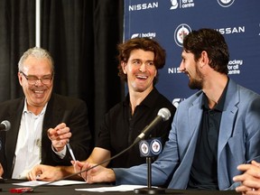 Winnipeg Jets teammates Mark Scheifele (centre) and Connor Hellebuyck (right) laugh after signing contracts with general manager Kevin Cheveldayoff at Hockey For All Centre on Tues., Oct. 10, 2023. KEVIN KING/Winnipeg Sun