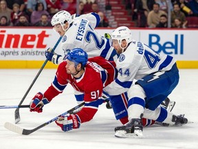 Canadiens' Sean Monahan is brought down by Tampa Bay Lightning's Calvin de Haan and Michael Eyssimont during the first period of a National Hockey League game in Montreal Tuesday Nov. 7, 2023. Eyssimont was penalized on the play.