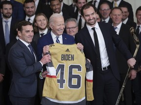 U.S. President Joe Biden holds up a sweater presented by Vegas Golden Knights' Mark Stone (R) and President of Hockey Operations George McPhee.