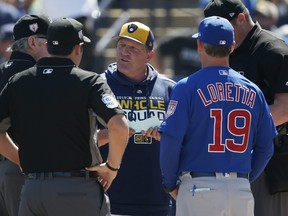Milwaukee Brewers bench coach Pat Murphy talks with Chicago Cubs bench coach Mark Loretta and the umpires before a spring training game.