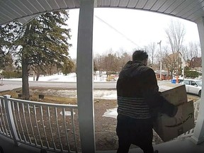 An alleged thief carries parcels away from a porch in this 2019 image.