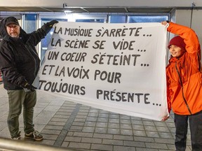 Sylvain Lachapelle and his grandson Zak Nault with the banner they brought to the national funeral for Cowboys Fringant lead singer Karl Tremblay at the Bell Centre in Montreal Tuesday Nov. 28, 2023. The banner reads "the music stops. the stage empties, a heart dies, and the voice forever present."