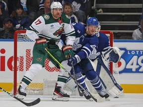 Marcus Foligno (17) of the Minnesota Wild battles against Jake McCabe (22) of the Toronto Maple Leafs during the second period in an NHL game at Scotiabank Arena on Oct. 14, 2023, in Toronto.