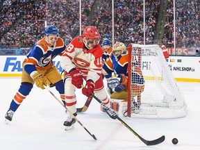A.J. Greer (18) of the Calgary Flames battles Philip Broberg (86) of the Edmonton Oilers for the puck during the 2023 Tim Hortons NHL Heritage Classic at Commonwealth Stadium on Oct. 29, 2023, in Edmonton, Alberta, Canada. (Photo by Derek Leung/Getty Images)
