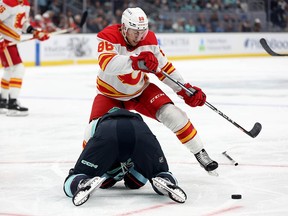 Andrew Mangiapane #88 of the Calgary Flames plays the puck after checking Jared McCann #19 of the Seattle Kraken during the first period at Climate Pledge Arena on November 4, 2023 in Seattle, Washington.