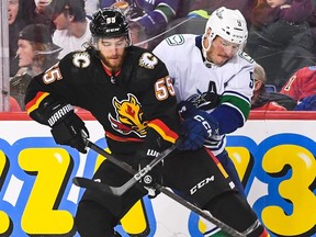 Noah Hanifin of the Calgary Flames battles J.T. Miller of the Vancouver Canucks for the puck at Scotiabank Saddledome on November 16, 2023 in Calgary.