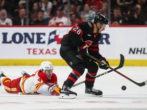 Connor Zary #47 of the Calgary Flames dives for the puck as Erik Brannstrom #26 of the Ottawa Senators skates with it during the third period at Canadian Tire Centre on Nov. 11, 2023 in Ottawa, Ontario, Canada.