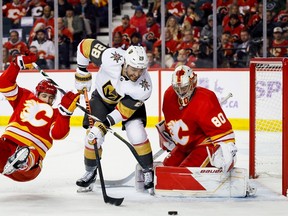 Calgary Flames defenceman Dennis Gilbert collides with Vegas Golden Knights forward William Carrier in front of Flames goaltender Dan Vladar at the Scotiabank Saddledome in Calgary on Monday, Nov. 27, 2023.