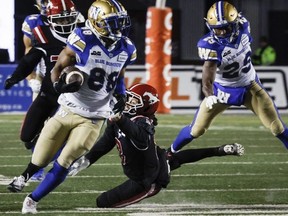 Winnipeg Blue Bombers wide receiver Rasheed Bailey, centre, escapes a tackle from Calgary Stampeders defensive back Nick Statz on his way to scoring a touchdown on Saturday. The Bombers are ehaded back to the Grey Cup.