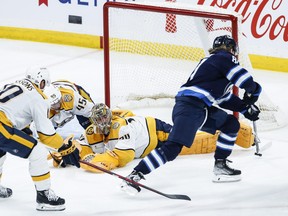 Winnipeg Jets' Kyle Connor scores a nifty back-hand goal on Predators' goaltender Juuse Saros as Colton Sissons (10) and Alexandre Carrier (45) can't stop him last night in Winnipeg.