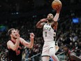 Milwaukee Bucks' Damian Lillard goes in for a layup past Raptors' Jakob Poeltl on Wednesday, Nov. 15, 2023 at Scotiabank Arena.