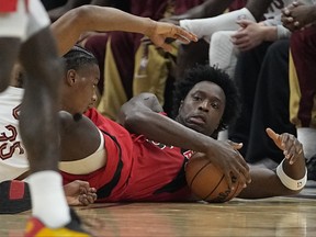 Raptors’ OG Anunoby gathers in a loose ball on the floor while Isaac Okoro reaches for it during last night’s game in Cleveland.