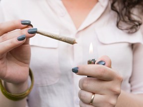A young woman holds a lighter to a joint.