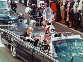 President John F. Kennedy smiles at the crowds lining their motorcade route in Dallas, Texas, on November 22, 1963.