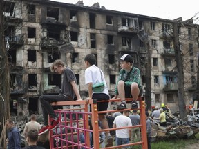 Ukrainian children abducted by Russia during its assault on their country are sharing the stories of their captivity with Canadian parliamentarians, in hopes they will help rescue others. Children look at the scene of the latest Russian rocket attack that damaged a multi-storey apartment building in Kryvyi Rih, Ukraine, Tuesday, June 13, 2023.
