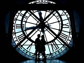 A couple poses for a photo near a giant clock at the Musee d'Orsay in Paris, on July 9, 2023.