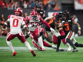 BC Lions quarterback Vernon Adams Jr. (3) runs with the ball before sliding down between the Calgary Stampeders’ Micah Awe and Kobe Williams during the CFL West Division semifinal at BC Place in Vancouver on Saturday, Nov. 4, 2023.