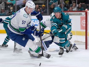 Vancouver Canucks defenseman Tyler Myers skates toward the puck next to San Jose Sharks left wing Fabian Zetterlund during the first period of NHL game in San Jose, Calif., Saturday, Nov. 25, 2023.