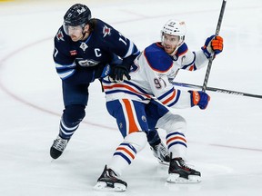 Winnipeg Jets' Adam Lowry (17) and Edmonton Oilers' Connor McDavid (97) collide during first period NHL action in Winnipeg on Thursday, November 30, 2023.