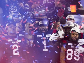 Alouettes linebacker Darnell Sankey hoists the Grey Cup as linebacker Avery Williams (2) and returner James Letcher Jr. (89) look on Sunday night.
