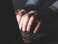 The hands of a man typing on a laptop keyboard.