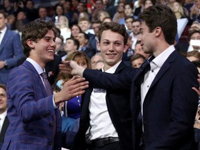 Jack Hughes, the first overall pick by the New Jersey Devils in the 2019 NHL draft at Rogers Arena, is congratulated by brothers Luke (centre) and Quinn (right).