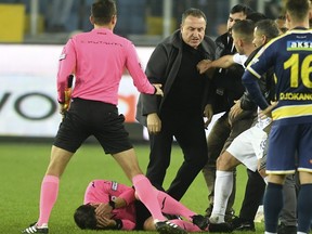 Referee Halil Umut Meler holds his face as he lies on the ground after being punched by MKE Ankaragucu president Faruk Koca, centre, at the end of the Turkish Super Lig match.