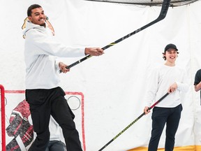 San Antonio Spurs rookie Victor Wembanyama takes a shot with a hockey stick as Chicago Blackhawks' Connor Bedard watches.