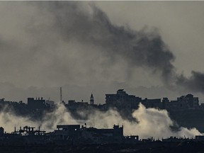 This picture taken from southern Israel near the border with the Gaza Strip shows smoke ammunition fired by Israeli artillery in the foreground and smoke rising from buildings in the background, after battles resumed between Israel and Hamas militants, on December 2, 2023. Israel brushed off international calls to renew an expired truce on December 2 and pushed on with its devastating bombing campaign against Hamas militants in densely-inhabited Gaza.