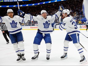 John Tavares, centre, of the Toronto Maple Leafs celebrates his assist and 1,000th NHL point against the New York Islanders during the third period at UBS Arena on Monday, Dec. 11, 2023, in Elmont, N.Y. Despite the heroics, the Islanders defeated the Maple Leafs 4-3 in overtime.