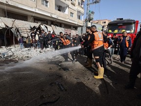 Palestinian emergency staff wash the site where a car was struck in an Israeli airstrike in Rafah in the southern Gaza Strip on December 22, 2023, amid continuing battles between Israel and the militant group Hamas.