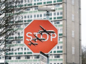 A red stop sign with three military drones on it , a piece by Banksy, was taken in the middle of the day by a man with bolt cutters.