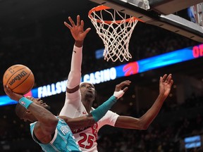 Charlotte Hornets guard Terry Rozier (3) goes up to the net under pressure from Toronto Raptors forward Chris Boucher (25) during first half NBA basketball action in Toronto, Monday, Dec. 18, 2023.
