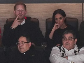 Prince Harry, back left, and Meghan Markle, back right, the Duke and Duchess of Sussex, watch the Vancouver Canucks and San Jose Sharks play during the first period of an NHL hockey game in Vancouver on Monday, Nov. 20, 2023.