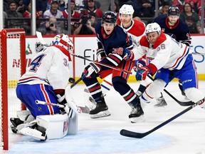 Montreal Canadiens' goaltender Jake Allen (34) makes a save on Winnipeg Jets' Morgan Barron (36) as he is checked by Jesse Ylonen (56) during the second period of NHL action in Winnipeg, Monday, Dec. 18, 2023. THE CANADIAN PRESS/Fred Greenslade