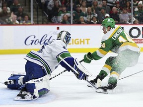 Vancouver Canucks goaltender Casey DeSmith, left, makes a save on a shot by Minnesota Wild center Joel Eriksson Ek (14) during the second period of an NHL hockey game Saturday, Dec. 16, 2023, in St Paul, Minn.