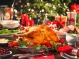 Christmas turkey dinner with ham, Christmas tree, candles and plates in background.