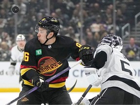 Vancouver Canucks left wing Andrei Kuzmenko, left, and Los Angeles Kings defenceman Sean Durzi watch the puck fly by during the first period of an NHL hockey game Monday, April 10, 2023, in Los Angeles.