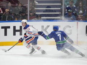 Vancouver Canucks' Carson Soucy (7) grabs Edmonton Oilers' Lane Pederson (19) during the first period of a preseason NHL hockey game in Vancouver, B.C., Saturday, Sept. 30, 2023.