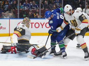 Vegas Golden Knights goalie Adin Hill stops Vancouver Canucks' J.T. Miller as Vegas' Alex Pietrangelo  defends during the first period of NHL game in Vancouver, on Thursday, November 30, 2023.