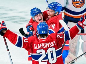 Canadiens' Cole Caufield (22) celebrates with teammates Nick Suzuki (14) and Juraj Slafkovsky (20) after scoring against the New York Islanders in Montreal on Saturday, Dec. 16, 2023.